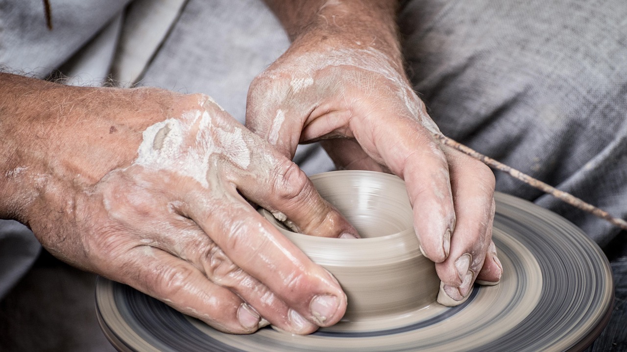 Mani di un artigiano che modellano un vaso di argilla al tornio